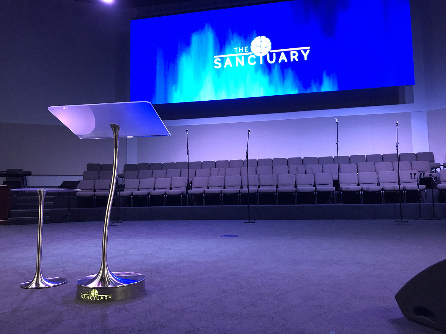 Brightly lit stage with custom signage for The Sanctuary event or church.