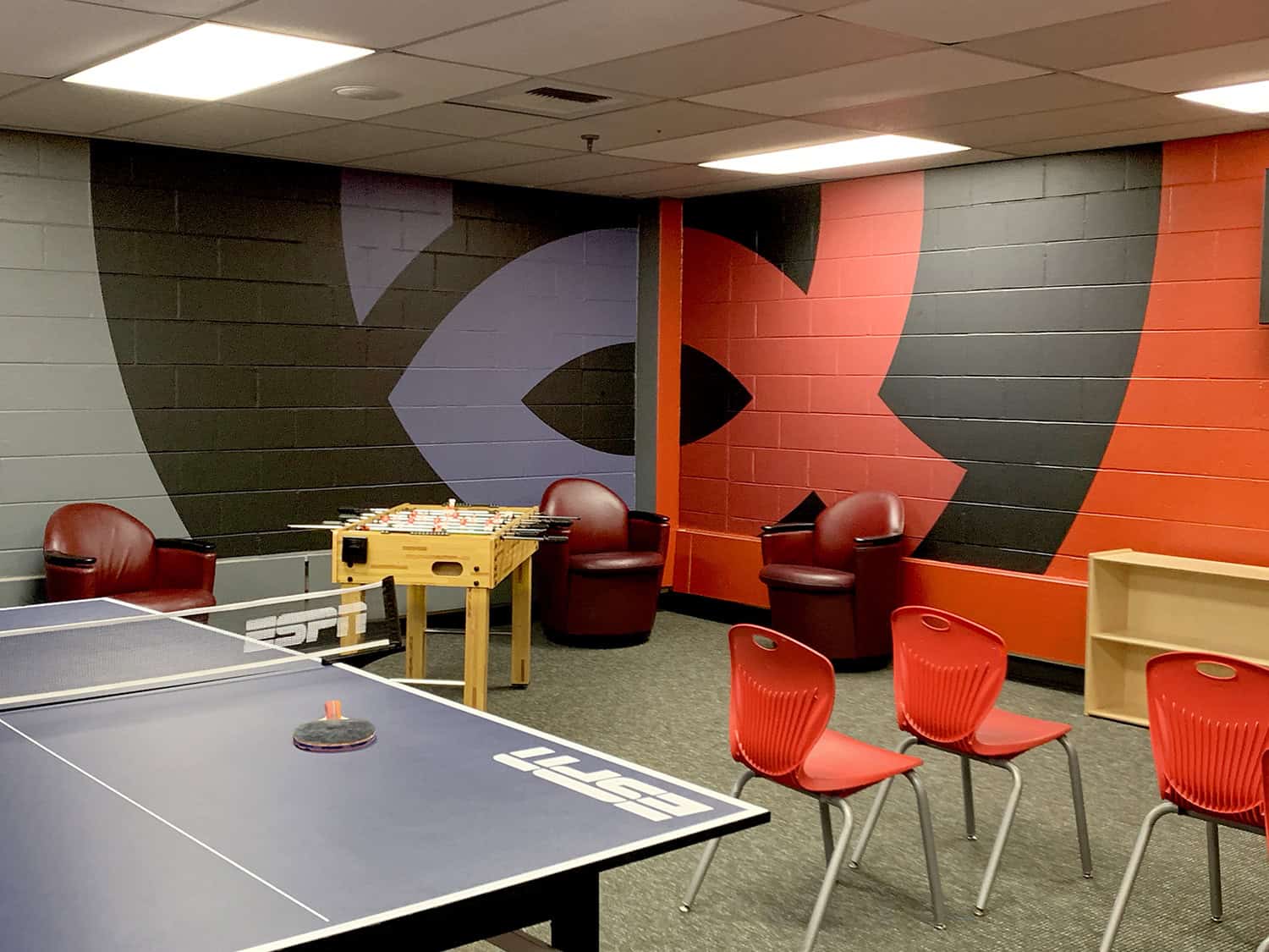 Colourful mural wall art at indoor recreational game room with table tennis and foosball.