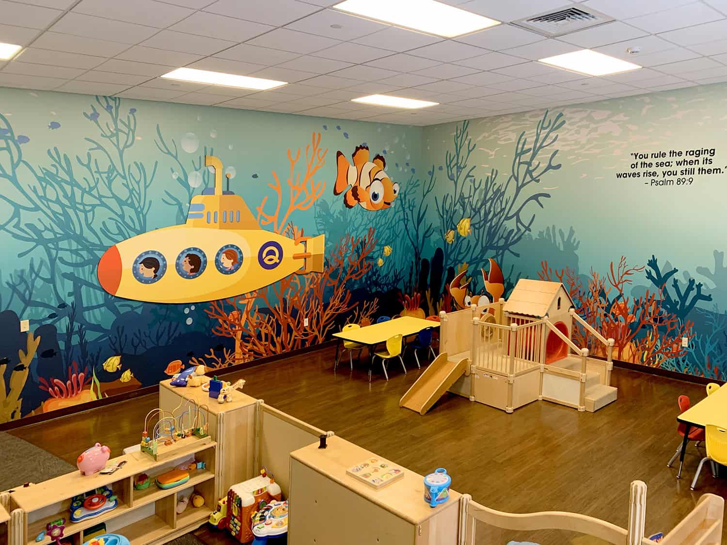 Vibrant underwater-themed children’s playroom with colourful wall mural and play equipment.