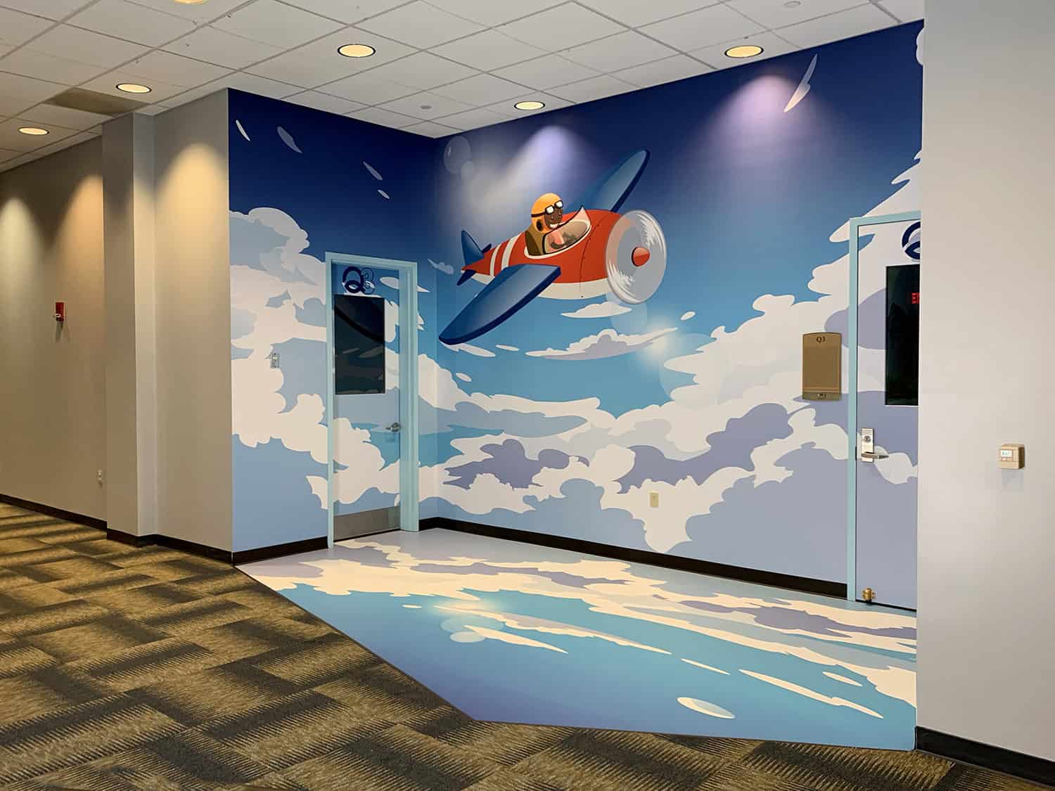 Vibrant airplane-themed wall mural with clouds and sky background, ideal for creative interior signage and decor.