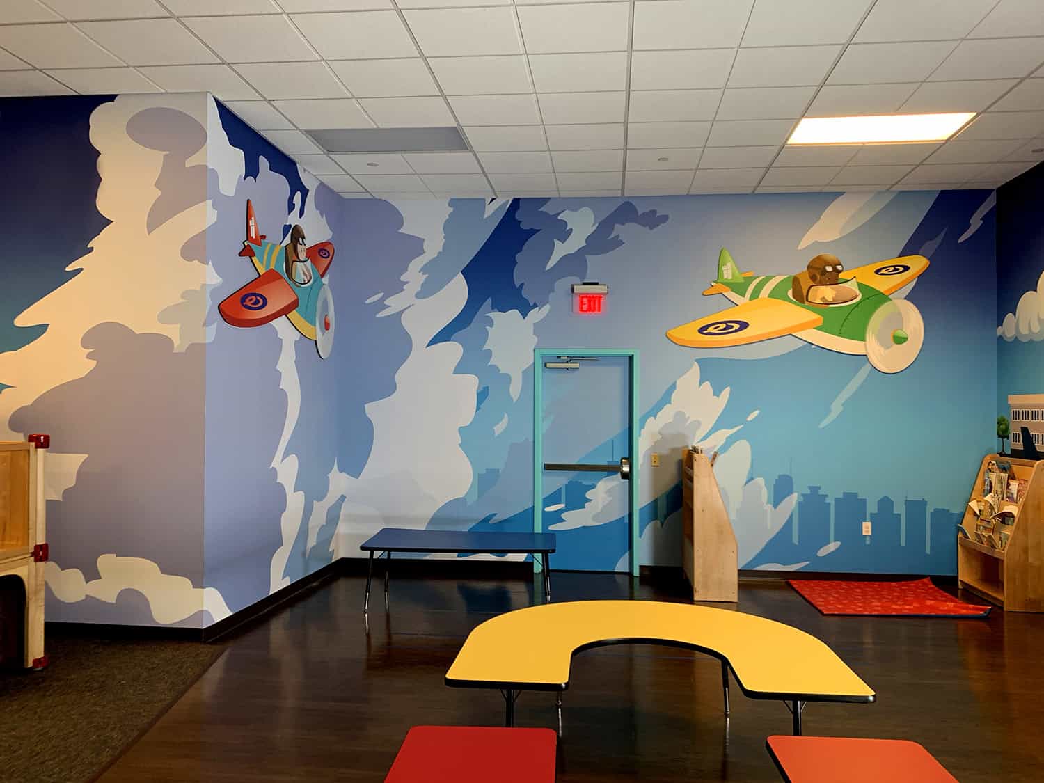 Bright indoor children's play area with colorful airplane wall murals and playful decor.