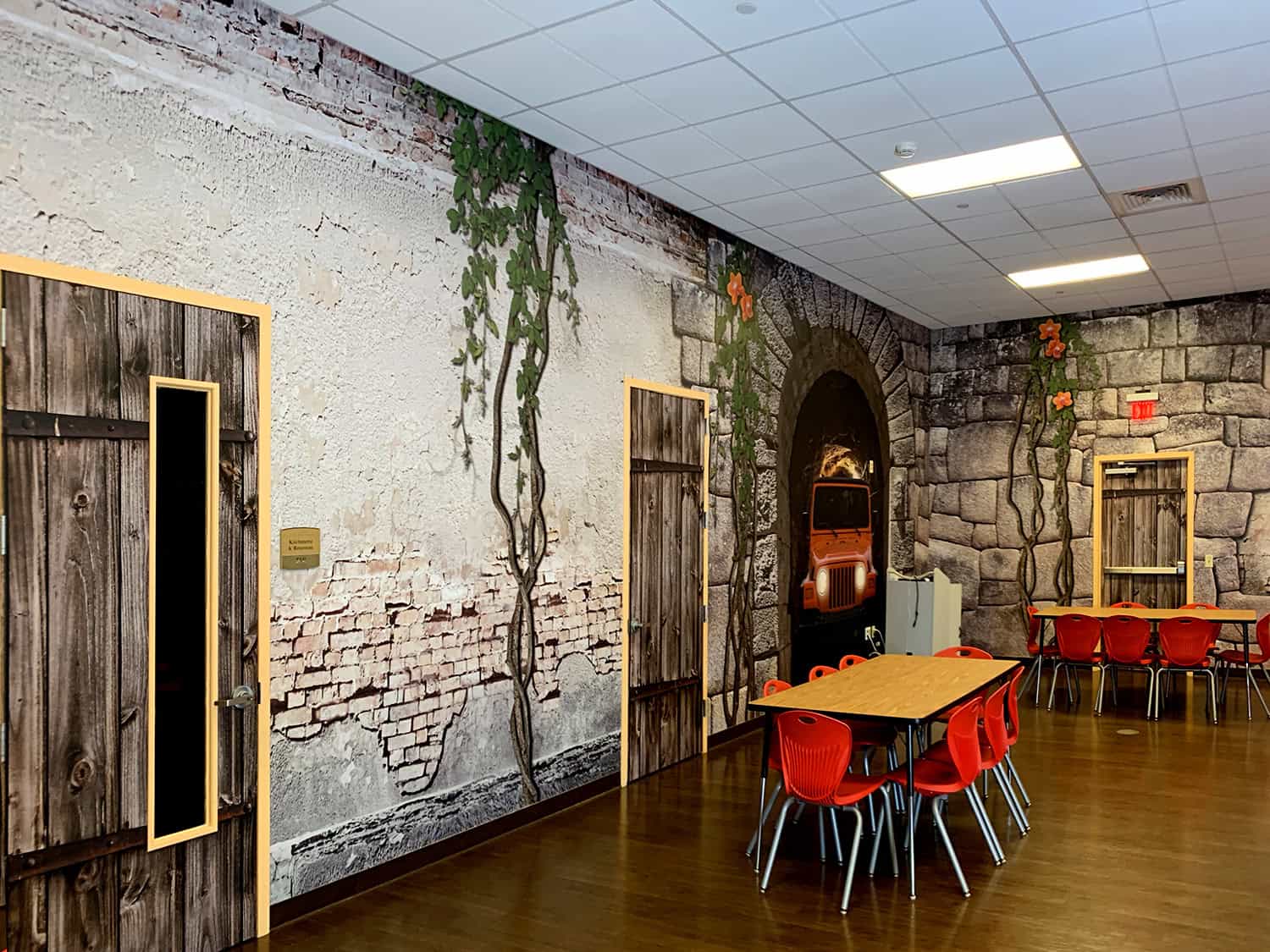 Vibrant sign shop interior with rustic brick wall decor and creative wall art featuring vintage vehicle and plant motifs.