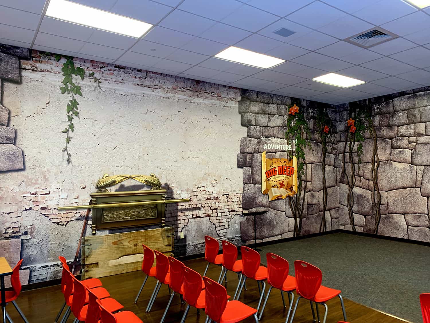 Vibrant church or community room with stone wall murals and red chairs for events.