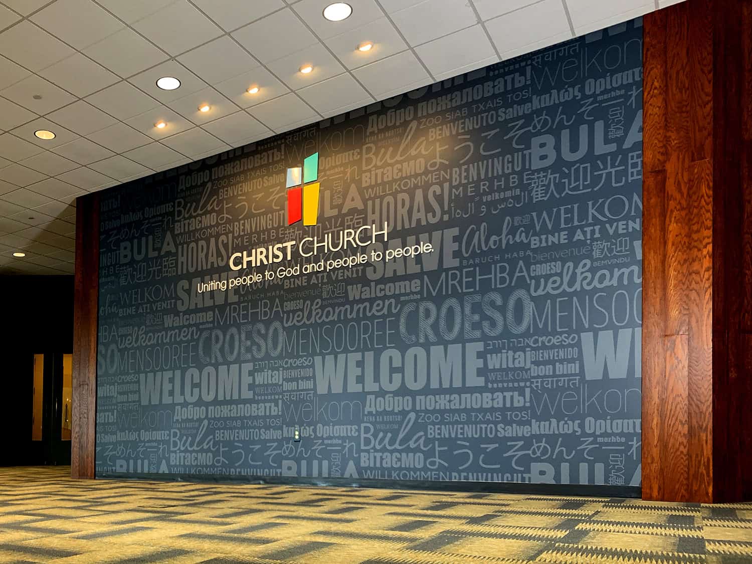 Colourful welcome signage at Christ Church with multi-language "Welcome" words.