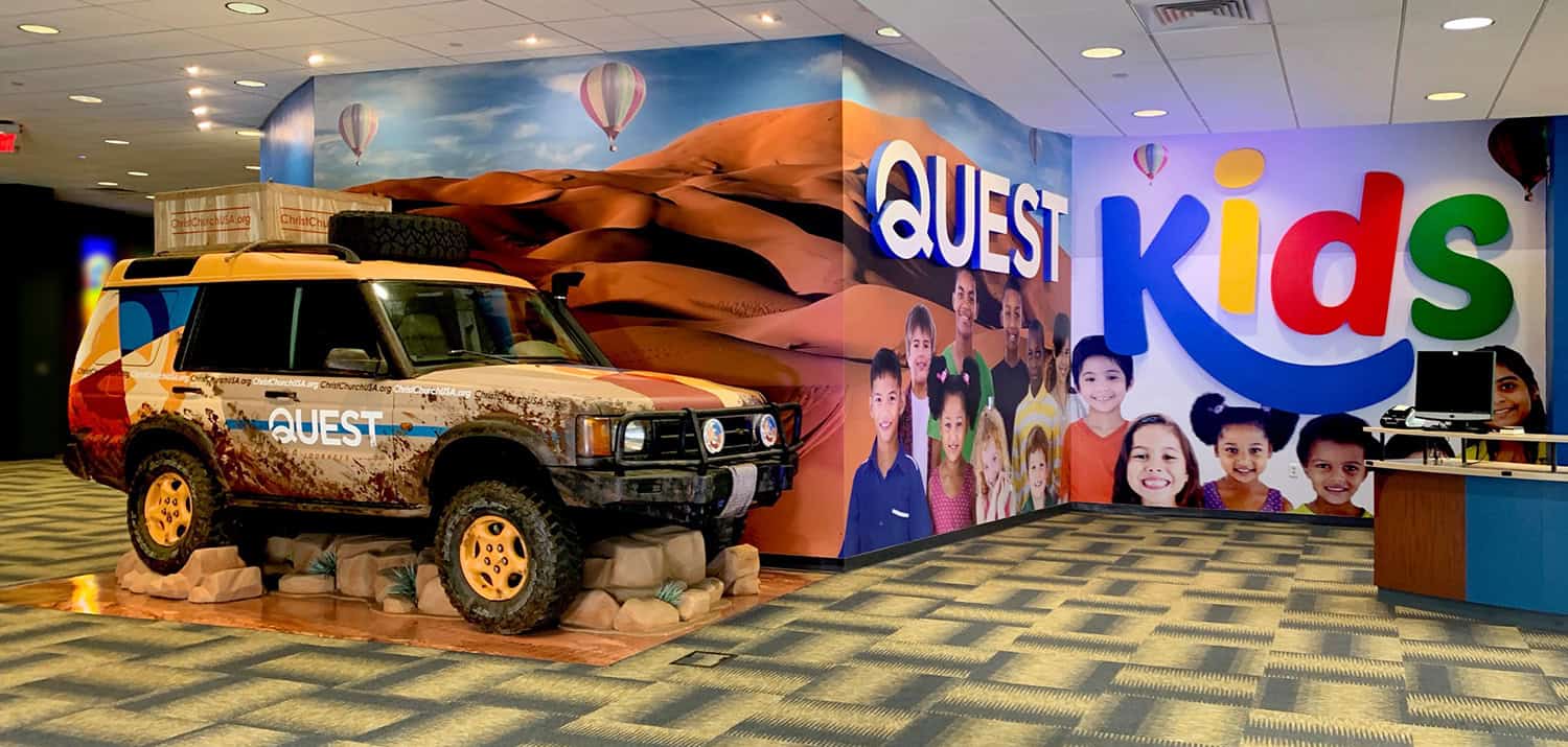 Adventure-themed children's play area with vibrant signage and a decorated vehicle display.