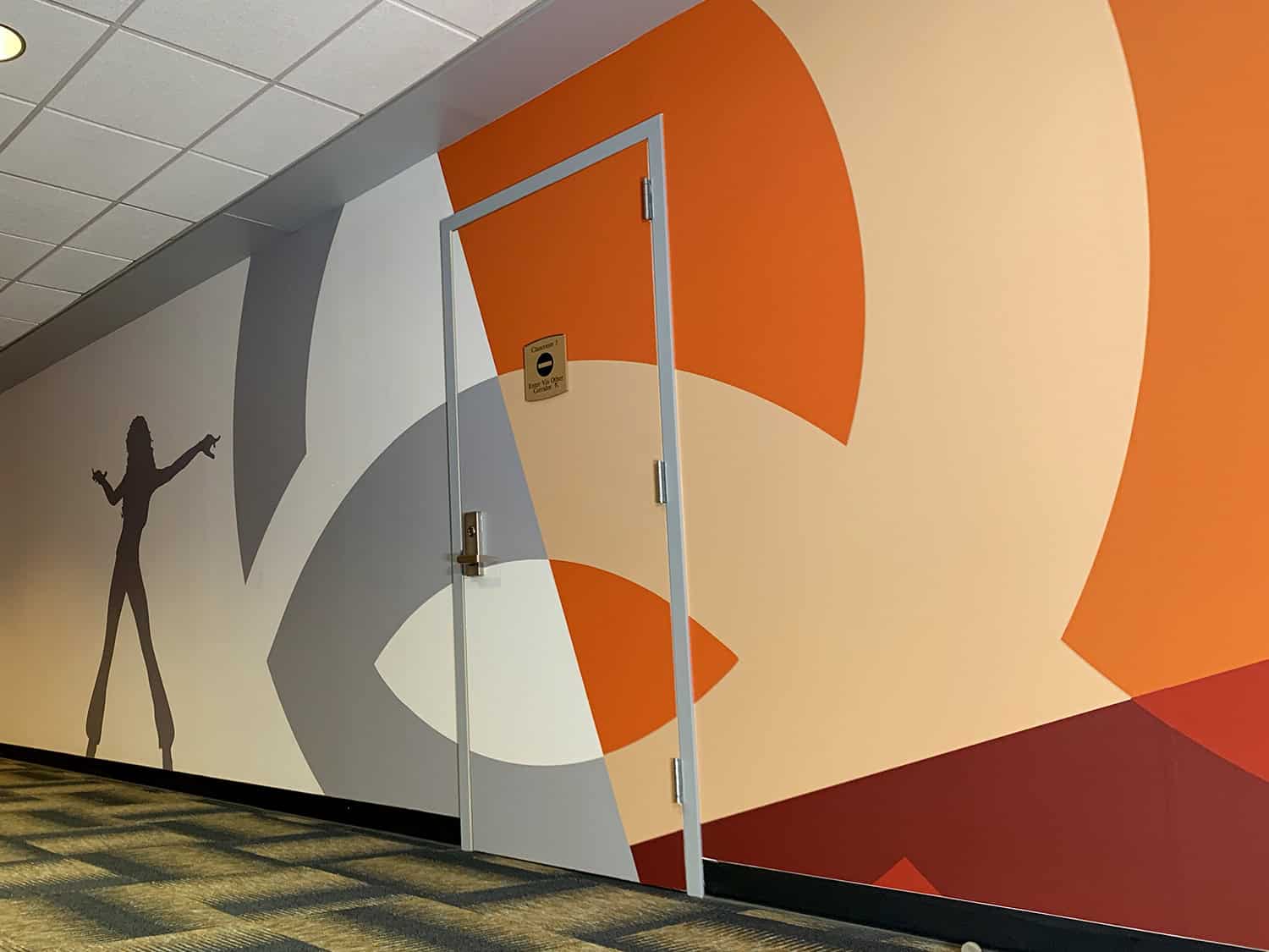 Vibrant abstract mural with bold colours and a silhouetted figure in an indoor space.