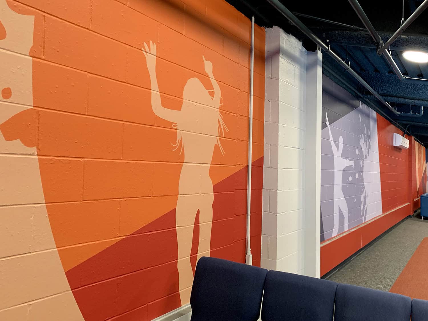 Vibrant orange and purple wall murals featuring dynamic sports-themed silhouettes and graphics.