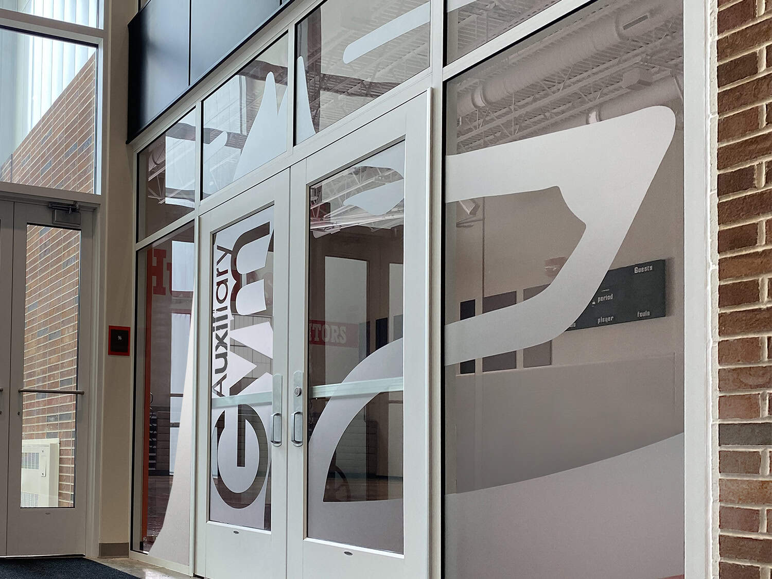 Clear glass doors with decorative vinyl signage for corporate office entrance.