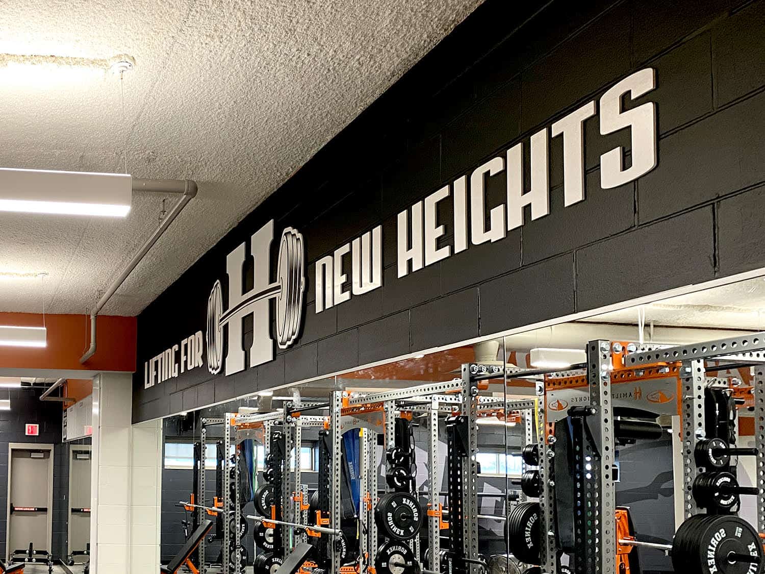 Bold "Signworks" gym signage with modern LED backlit letters in fitness centre interior.