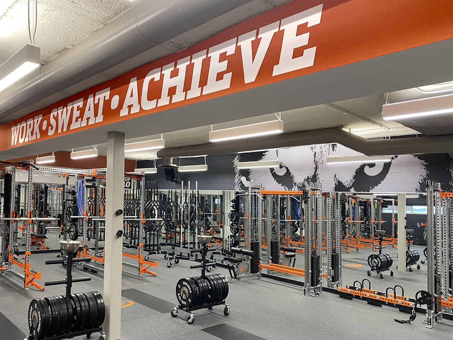 Bold motivational gym sign with "Work Sweat Achieve" message in fitness centre.