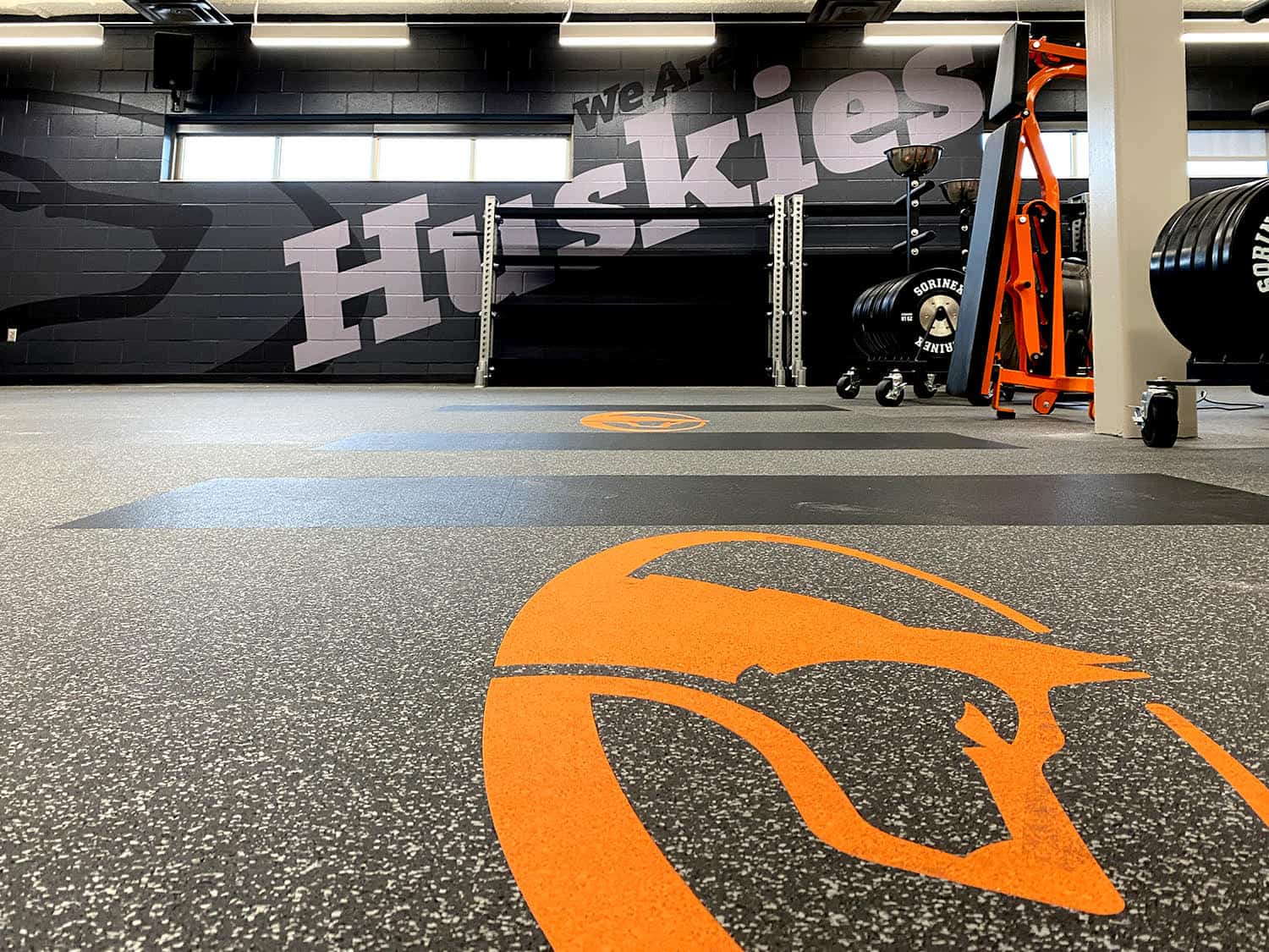 Bright orange sports court marking with basketball icon at gym flooring.