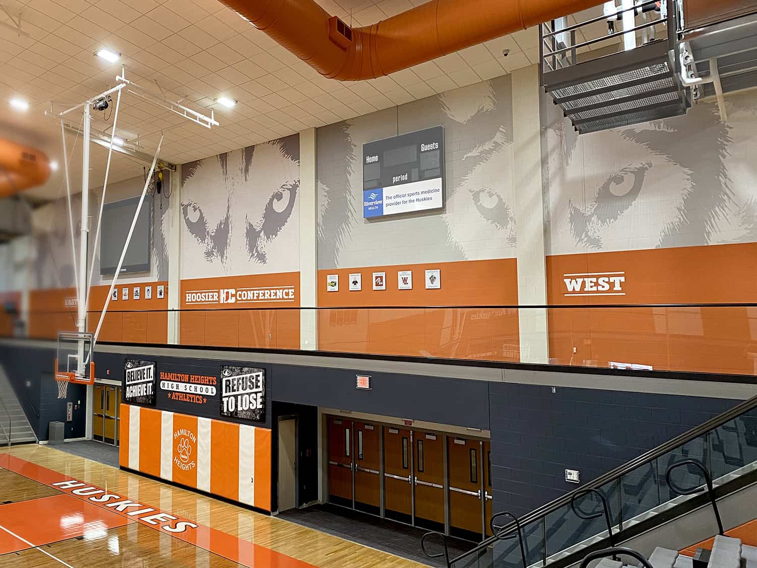 Bold wall graphics of a wolf's face in a sports gymnasium, with branding and signage.
