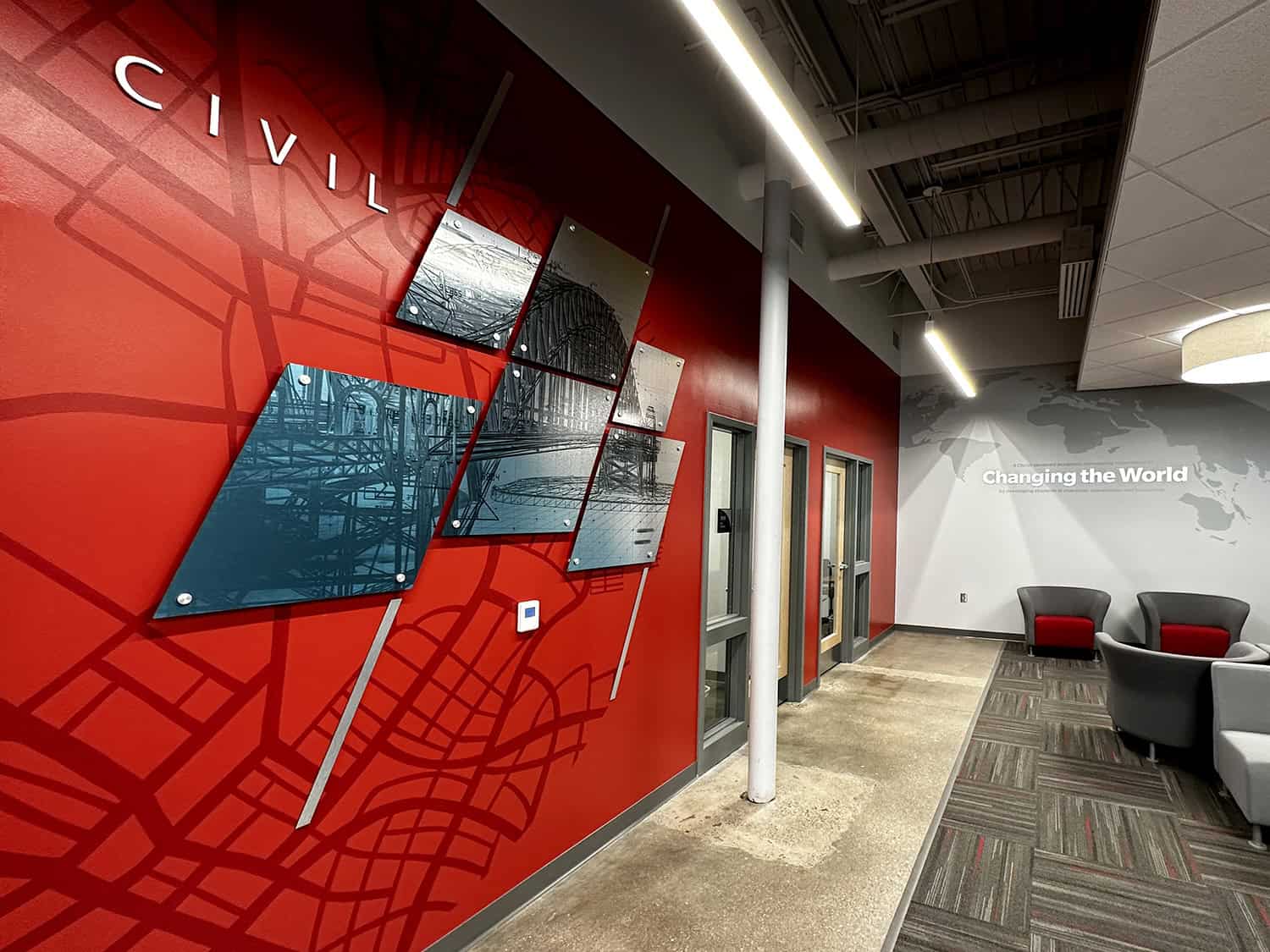 Vibrant red wall with custom branded signage and modern art displays in office reception area.