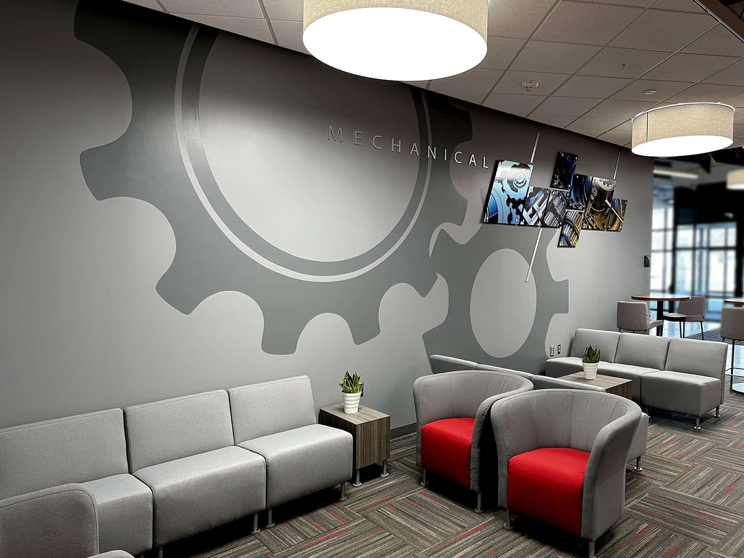 Modern mechanical engineering office waiting area with gear wall art and lounge chairs.