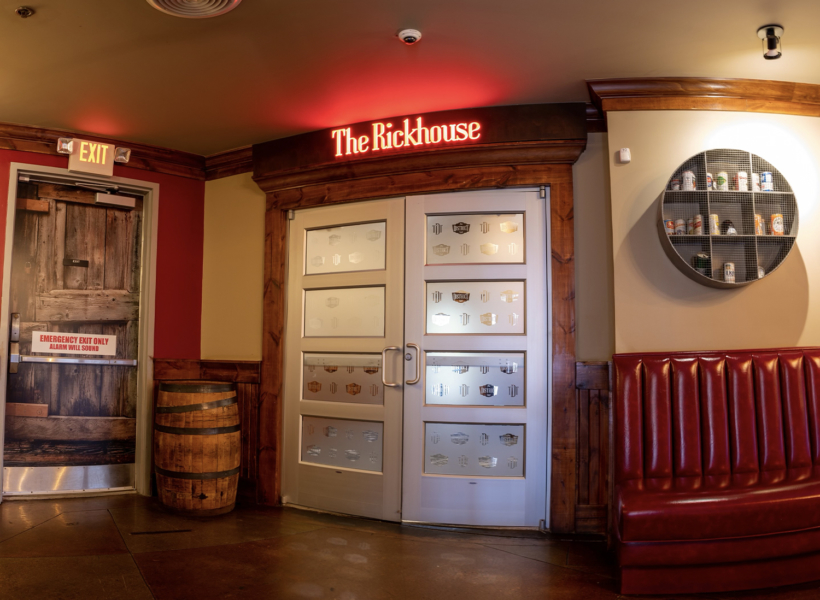 Vibrant indoor restaurant entrance with illuminated "The Rickhouse" sign and rustic decor.