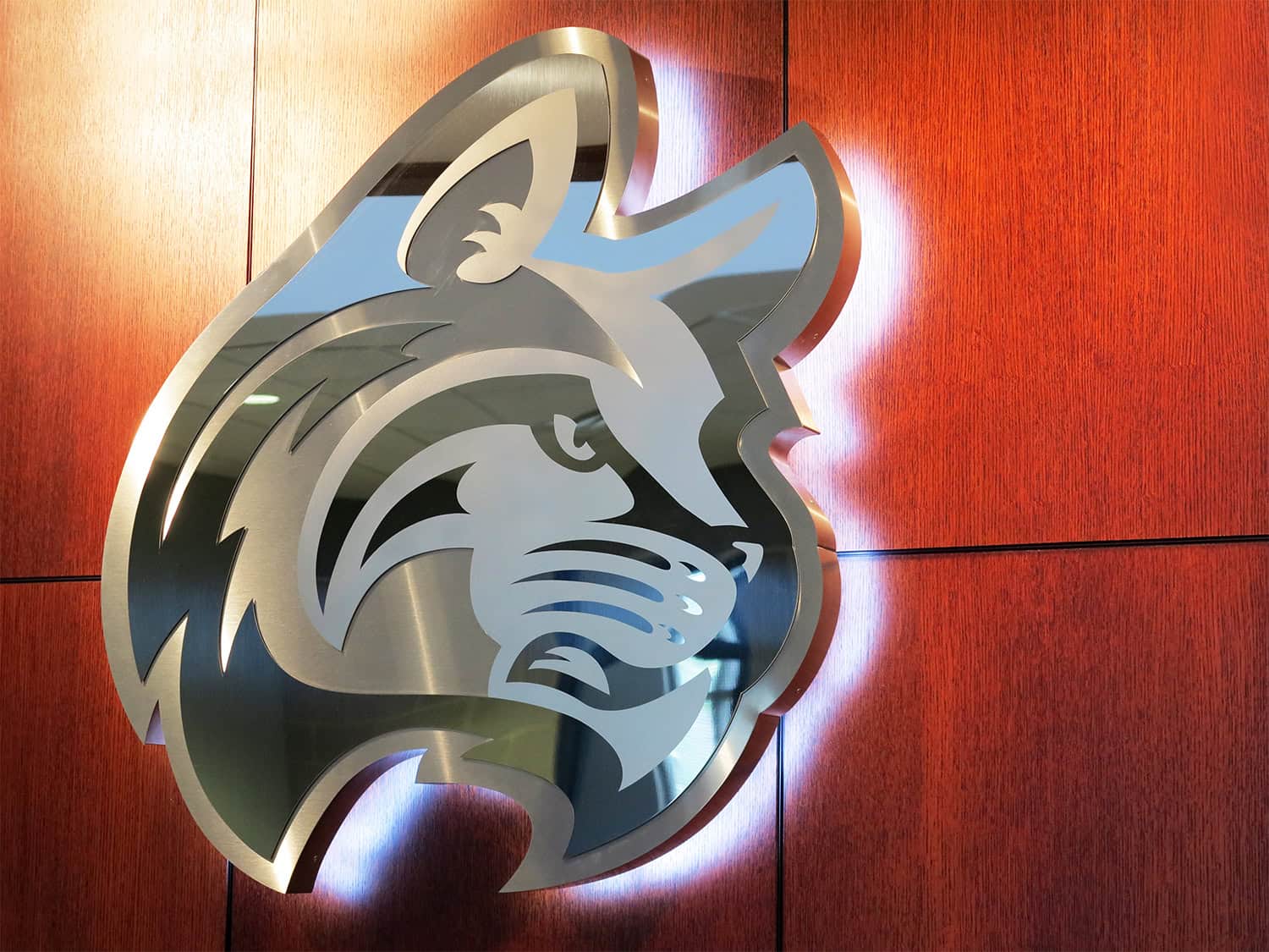 3D lion head business sign in metallic finish on red wall, professional signage design and manufacturing, logo signage, corporate branding, custom sign solutions.