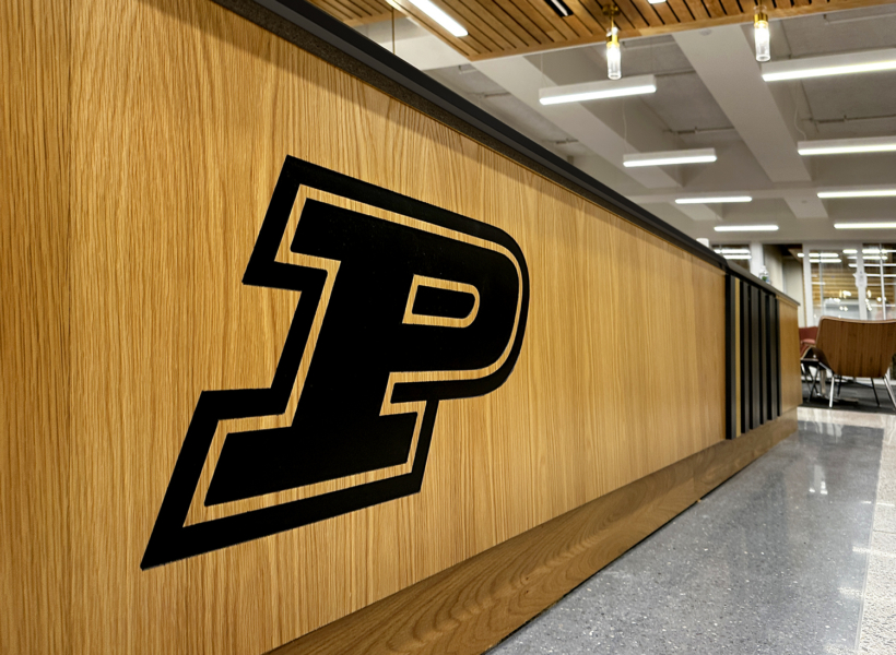 Illuminated sign with bold black logo on wooden counter in modern interior space.