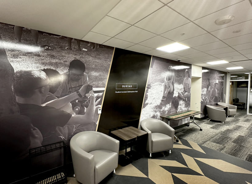 Vibrant black and white wall murals of students using mobile devices at university lounge area.