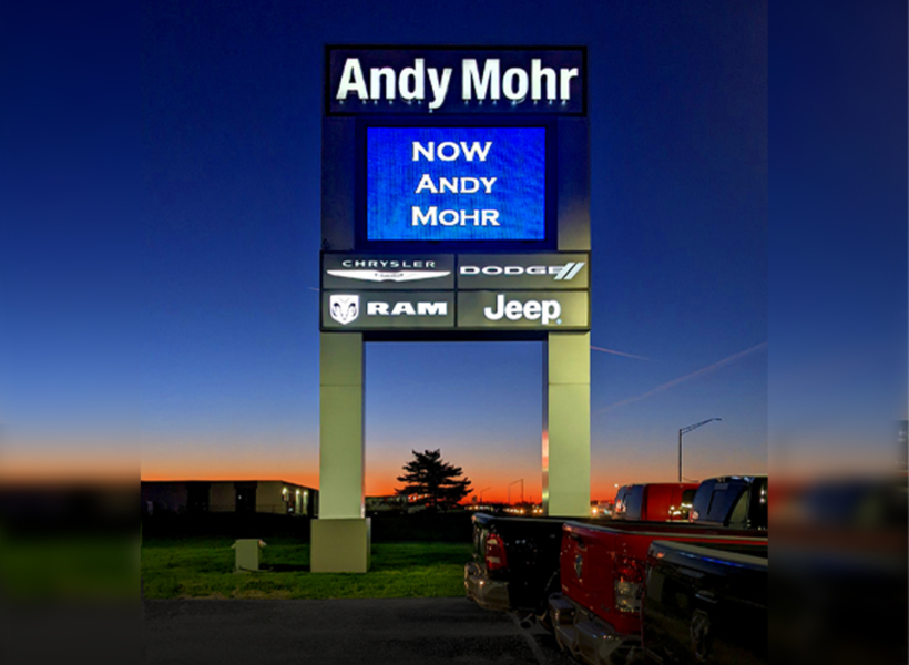 Bright digital signage advertising car dealership brands at dusk in Australia.