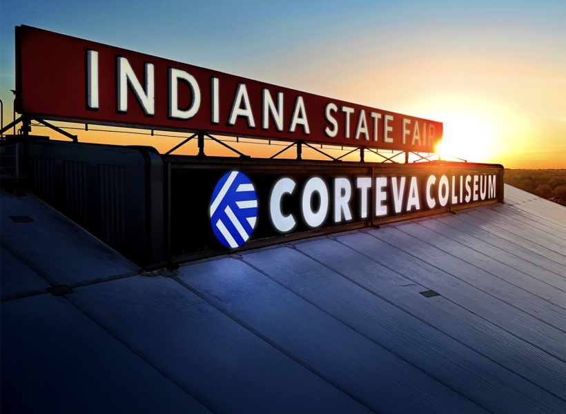 Bright illuminated signboards for Indiana State Fair and Corteva Coliseum at sunset.