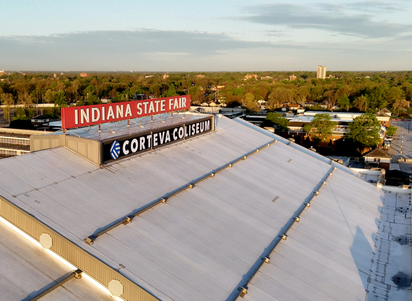 Large Indiana State Fair and Corteva Coliseum sign on rooftop at sunset, aerial view.