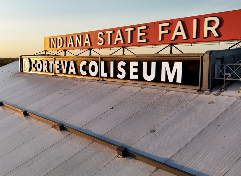 Vintage sign promoting Indiana State Fair and Corteva Coliseum, outdoor event signage.