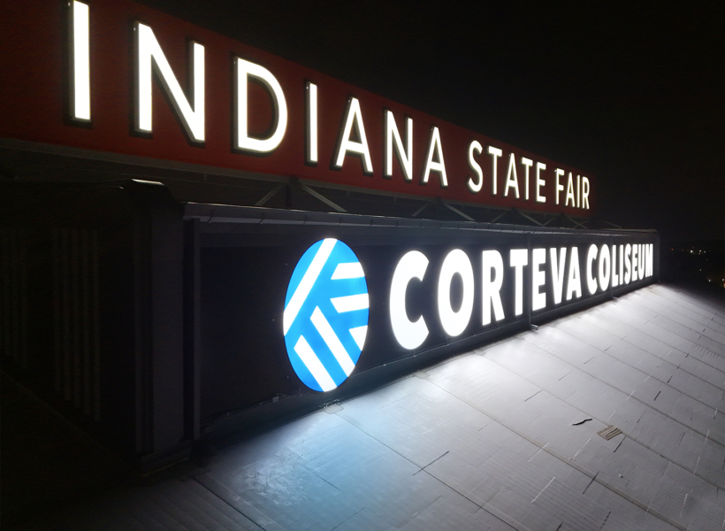 Illuminated sign for Indiana State Fair and Corteva Coliseum at night.