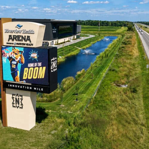 Large digital sign for Riverview Health Arena near a water feature and highway.